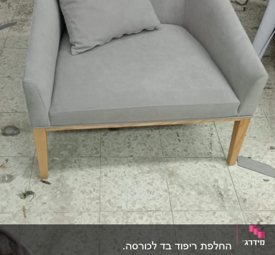כורסה מרופדת אפורה עם כרית תואמת על רצפה
